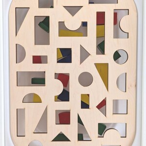 May include: A wooden board with various shapes cut out of it. The shapes are filled with colorful blocks. The board is labeled "The Wonder Games".