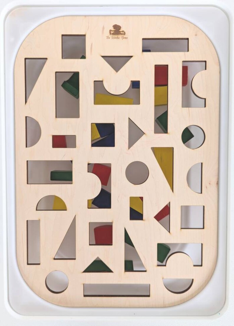 May include: A wooden board with various shapes cut out of it. The shapes are filled with colorful blocks. The board is labeled "The Wonder Games".