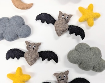 May include: A set of felt Halloween decorations featuring three brown bats with black wings, two gray clouds, a tan crescent moon, and two yellow stars.