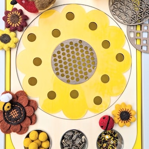 May include: A wooden sensory board with a yellow sunflower design, featuring a felt robin, ladybug, bee, and sunflower decorations. The board also includes small containers filled with sunflower seeds, rice, and yellow pom-poms.
