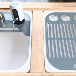 Puede incluir: Un fregadero de encimera blanco con un escurridor de platos gris y un dispensador de agua. El fregadero est&aacute; hecho de cer&aacute;mica y tiene un acabado blanco. El escurridor de platos est&aacute; hecho de pl&aacute;stico y tiene un acabado gris. El dispensador de agua est&aacute; hecho de acero inoxidable y tiene un acabado plateado.