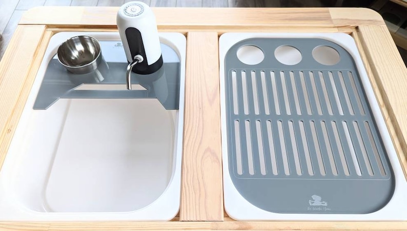 Puede incluir: Un fregadero de encimera blanco con un escurridor de platos gris y un dispensador de agua. El fregadero est&aacute; hecho de cer&aacute;mica y tiene un acabado blanco. El escurridor de platos est&aacute; hecho de pl&aacute;stico y tiene un acabado gris. El dispensador de agua est&aacute; hecho de acero inoxidable y tiene un acabado plateado.
