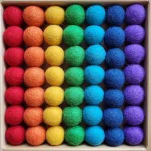 May include: A rainbow of felt balls arranged in a grid pattern. The balls are in shades of red, orange, yellow, green, blue, indigo, and violet.