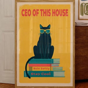Peut inclure: Affiche encadrée avec un chat noir portant des lunettes de soleil, assis sur une pile de livres. Le texte "CEO OF THIS HOUSE" est en orange. Les livres indiquent "Rule Softly" et "Stay Cool". Deux autres œuvres encadrées sont visibles.