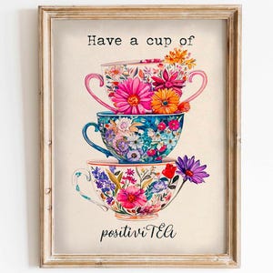 May include: A framed print with a floral design featuring three stacked teacups. The text "Have a cup of positivity Tea" is printed below the teacups.
