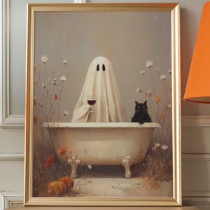 Può includere: Un'opera d'arte incorniciata raffigura un fantasma in una vasca da bagno, con un bicchiere di vino rosso, con un gatto nero. L'opera d'arte ha una cornice dorata ed è posta su un tavolo di legno. La scena è a tema Halloween.
