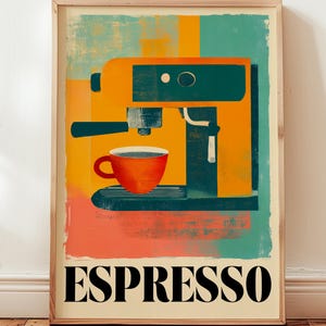Op de afbeelding: Een ingelijste kunstdruk met een espressomachine in oranje, teal en zwart. Een rode koffiekop staat onder de machine. Het woord "ESPRESSO" is in vette, zwarte letters onderaan de print gedrukt.