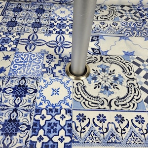 May include: A close-up of a silver metal table leg with a decorative base. The base is surrounded by a blue and white patterned tiled floor.