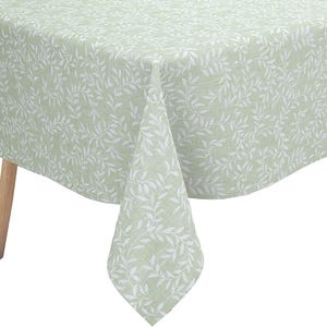 May include: A rectangular tablecloth in a soft sage green color featuring a repeating white botanical leaf pattern. The fabric drapes over the edges of a table with light-colored wooden legs, showcasing a consistent print across the entire surface.