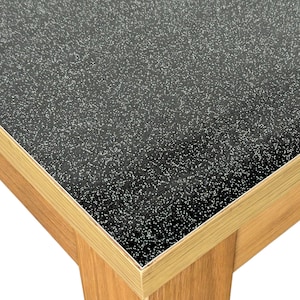 May include: Close-up of a black table top with a fine glitter finish. The table top is edged with a light wood trim.