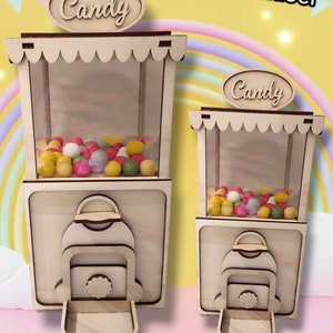 Può includere: Due distributori di caramelle in legno con finestre in plastica trasparente. I distributori sono dipinti di bianco e hanno un cartello con la scritta "Candy" in cima. I distributori sono pieni di caramelle colorate.