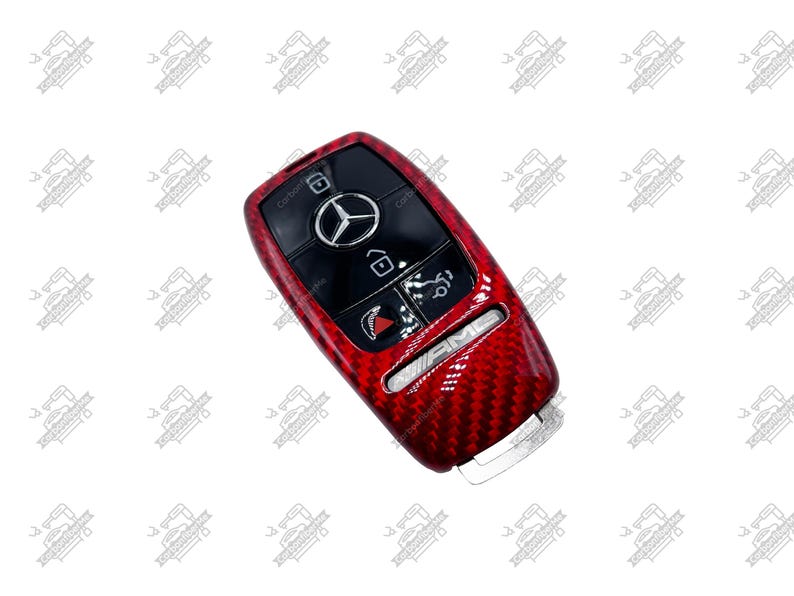 May include: Red carbon fiber car key fob cover with black buttons and the Mercedes-Benz logo. The key fob has the AMG logo and other symbols. The key fob is a car accessory.