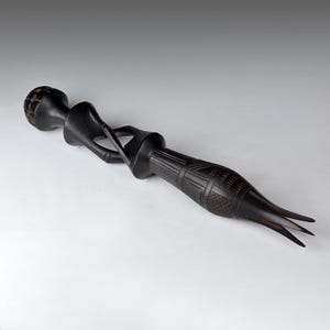 Puede incluir: Una escultura de madera negra de una mujer con una cabeza redonda y un cuerpo largo y delgado. La escultura está tallada con intrincados detalles y tiene una base de tres puntas.