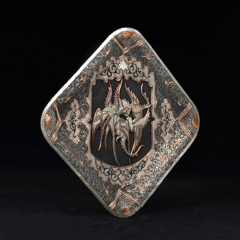 May include: A silver and copper square tray with an intricate design of birds and floral patterns. The tray has a textured surface and a black background.