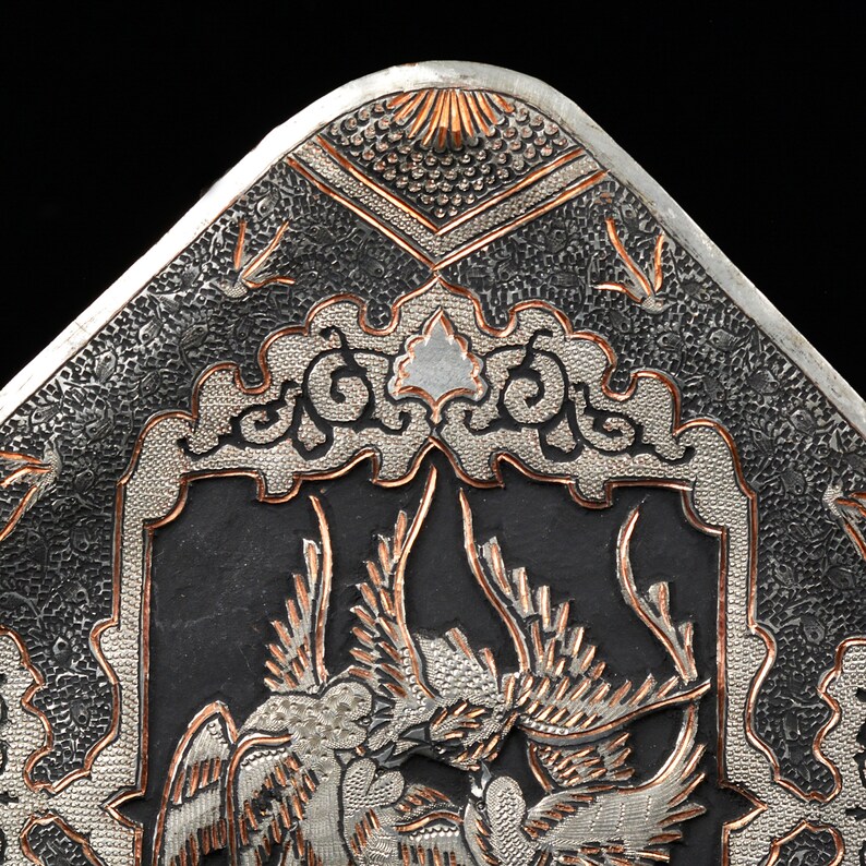 May include: A silver and copper tray with intricate floral and bird designs. The tray is decorated with a raised, textured pattern.