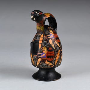 May include: A black ceramic vessel with a serpent-like head and a handle. The body is adorned with orange, white, and black patterns, and figures in blue, purple, and brown. The base is round and black.
