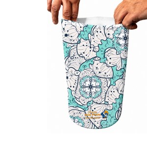 May include: A prosthetic limb cover featuring a light turquoise background with a repeating pattern of white, dark blue, and black line-art floral and mandala-style motifs. The text Amputee Sock Prints Made with Appeal is printed near the bottom.