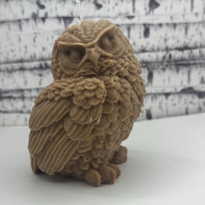 May include: A brown owl-shaped candle with detailed feathers and a white wick.