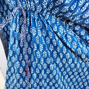 May include: A blue and white patterned cotton dress with a drawstring waist. The dress has a floral design and a tie at the waist.