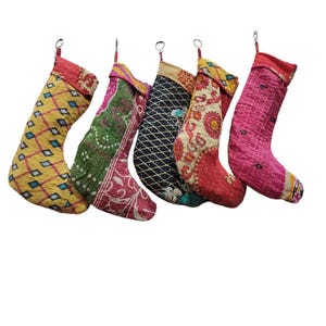 以下が含まれることがあります： カンタ生地で作られたカラフルなクリスマスストッキング5個セット。各ストッキングは、さまざまな色とパターンでユニークなパッチワークデザインが施されています。