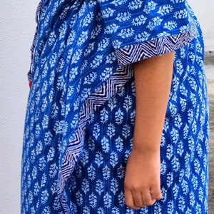 May include: A blue and white patterned dress with a tie at the waist. The dress has a loose fit and a flowing skirt.