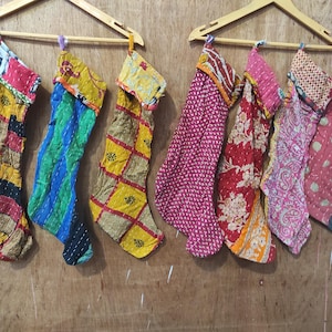 May include: A collection of colorful, patterned Christmas stockings hanging on a wooden background. The stockings feature various designs, including stripes, floral prints, and geometric patterns. Each stocking is unique, with a mix of red, yellow, blue, and green hues.