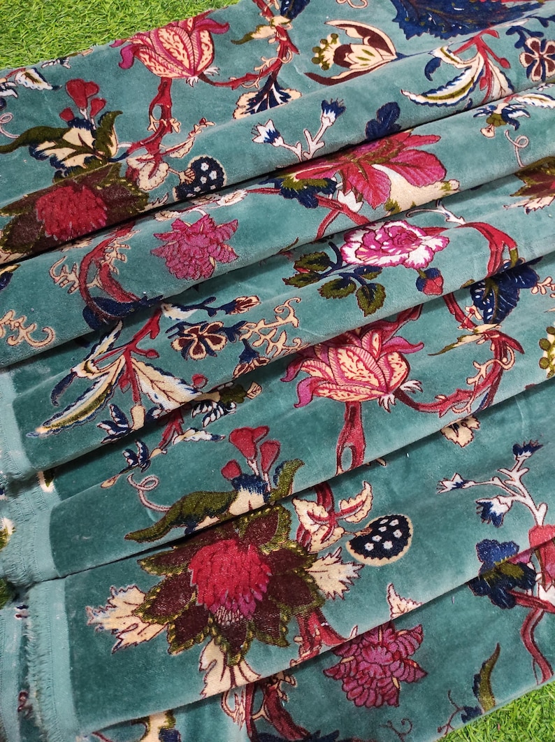 Puede incluir: Primer plano de tela turquesa con estampado floral. El dise&ntilde;o presenta grandes flores estilizadas en tonos rosa, rojo y crema, con follaje verde y azul. La tela est&aacute; doblada, mostrando su textura y los detalles del estampado.