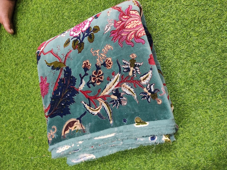 Puede incluir: Tela doblada de color verde azulado con un estampado floral en rosa, rojo y blanco. La tela tiene una textura suave y aterciopelada y est&aacute; doblada cuidadosamente. El dise&ntilde;o floral incluye hojas y otros elementos bot&aacute;nicos.