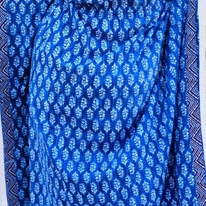 May include: A blue and white cotton fabric with a repeating floral pattern. The fabric has a white border with a blue and white geometric pattern.
