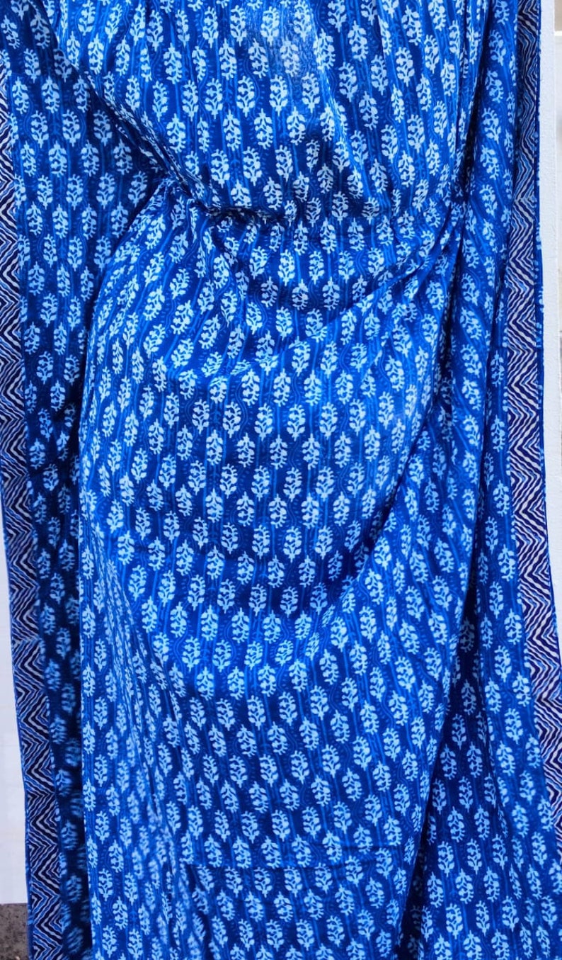 May include: A blue and white cotton fabric with a repeating floral pattern. The fabric has a white border with a blue and white geometric pattern.