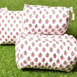 Puede incluir: Tres bolsas de tela blanca con estampados florales rosas. Las bolsas están acolchadas y tienen un cierre de cordón.