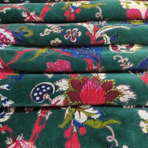 May include: Close-up of folded fabric with a dark green background and a floral pattern. The pattern includes red, pink, blue, and white flowers and leaves. The fabric appears to be velvet or a similar material.