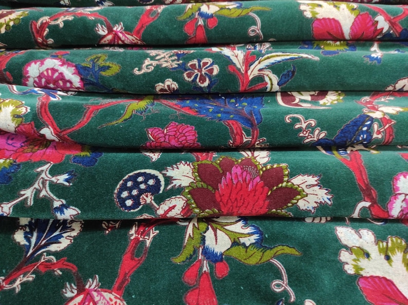 May include: Close-up of folded fabric with a dark green background and a floral pattern. The pattern includes red, pink, blue, and white flowers and leaves. The fabric appears to be velvet or a similar material.