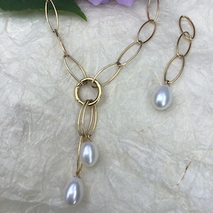 Un collier chic et unique en son genre, en or jaune 18 carats, orné de trois pendentifs en perles de culture d'eau douce de longueurs différentes. 3 300 €