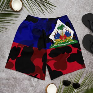 May include: Camouflage print shorts featuring the flag of Haiti. The flag is red, blue and green with a coat of arms in the centre. The shorts have a black, red and blue camouflage pattern.