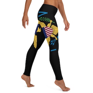 May include: Black leggings with a colourful design of the flag of the US Virgin Islands. The flag features a golden eagle with a shield and arrows.