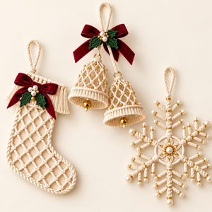 May include: Three macrame ornaments in cream cord: a stocking with fringe, a pair of bells, and a snowflake. Each piece features a deep red velvet bow, green fabric holly leaves, white faux pearls, and small gold metallic beads.