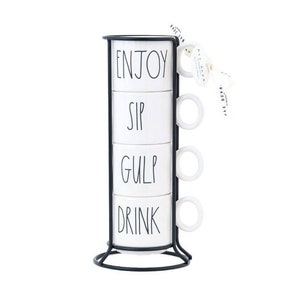 Pode incluir: Um conjunto de quatro canecas de cerâmica branca empilhadas em um suporte de metal preto. Cada caneca tem uma palavra preta: "ENJOY", "SIP", "GULP" e "DRINK". As canecas têm alças brancas. Uma etiqueta branca com texto preto pende do suporte.
