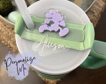 Puede incluir: Una taza de viaje verde con una tapa transparente y una pajita. La tapa tiene una pegatina de Mickey Mouse de color morado y una pegatina transparente con el nombre "Alison" escrito en ella. La taza tiene una pegatina blanca que dice "Personalízame".