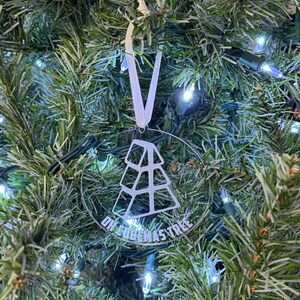 May include: A clear glass Christmas ornament with a white outline of a Christmas tree and the text "On Cubemas Tree".