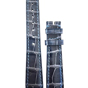 May include: A dark grey alligator watch strap with blue stitching. The strap is made of genuine leather and has a classic design.