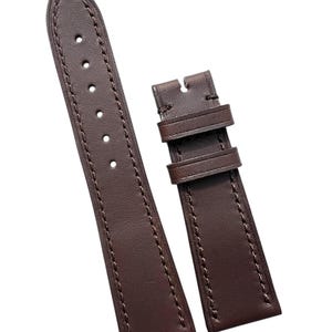 Könnte beinhalten: Ein braunes Lederarmband mit Nähten. Das Armband hat ein spitzes Ende und ein Schließenende.