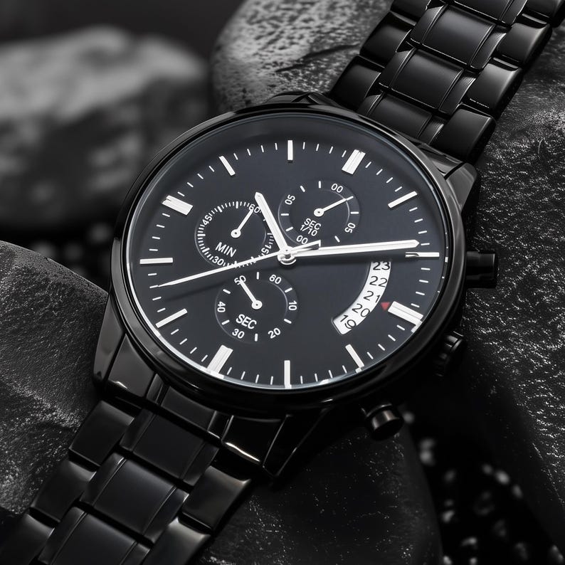 May include: A black wristwatch with a black metal band. The watch face has white markers and hands, with three sub-dials and a date display. The watch is set against a dark, textured background.