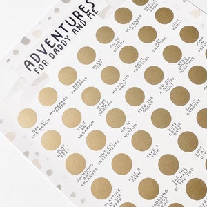 May include: A gold and white printable game card with the text "Adventures for Daddy and Me". The card features a grid of 25 circles, each containing a different activity for a father and child to do together. Some of the activities include "Make Pancakes", "Go to the Cinema", "Play Hide and Seek", "Visit an Aquarium", "Go on a Nature Hunt", "Feed the Ducks", "Take a Trip", "Decorate with Chalk", and "Jump in Puddles".