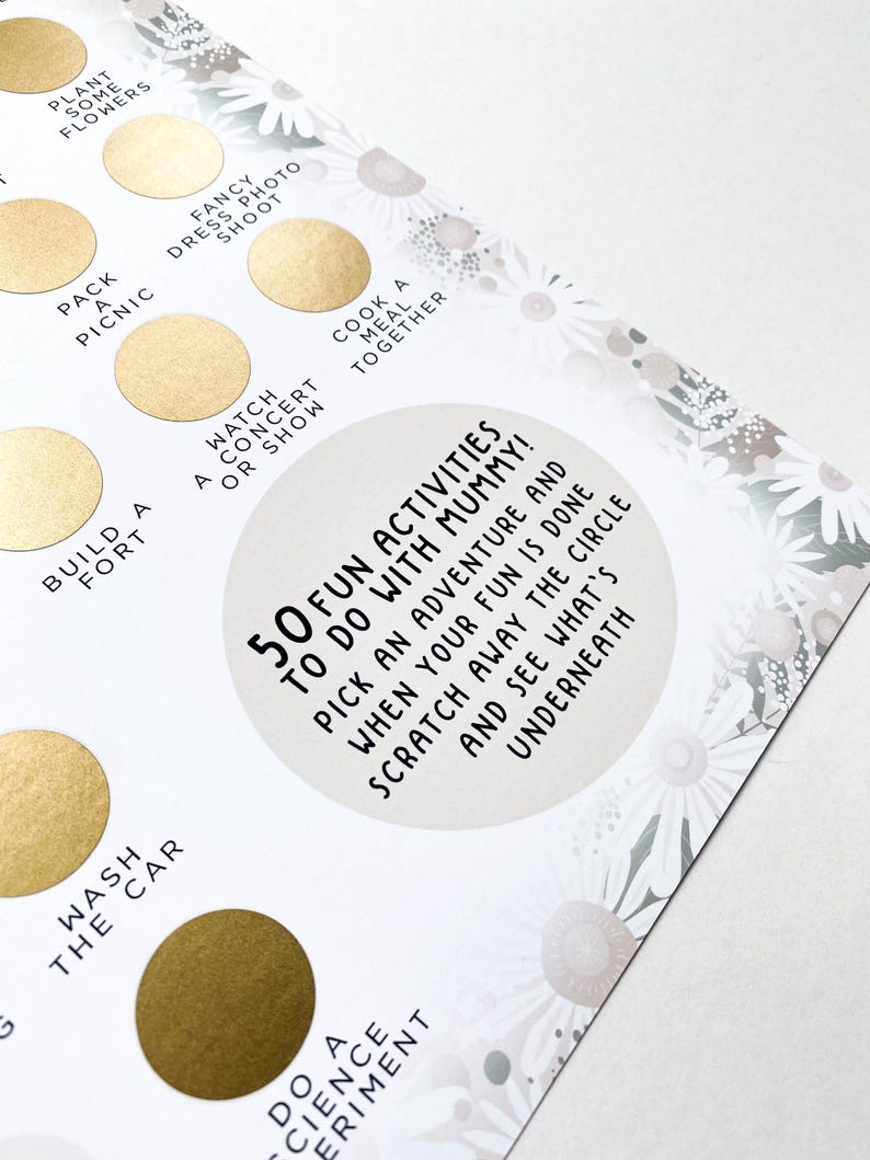 Op de afbeelding: Een witte kaart met een gouden cirkel in het midden. De cirkel heeft de tekst "50 Fun Activities to do with Mummy!"  Kies een avontuur en wanneer je klaar bent met je plezier, schraap de cirkel weg en zie wat eronder zit. De kaart is omringd door een wit madeliefjespatroon.