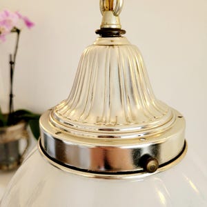 May include: A white glass globe pendant light fixture with a silver metal top and a decorative fluted design. The fixture is hanging from a chain.