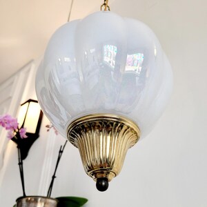 May include: A white iridescent glass pendant light fixture with a brass base and chain.