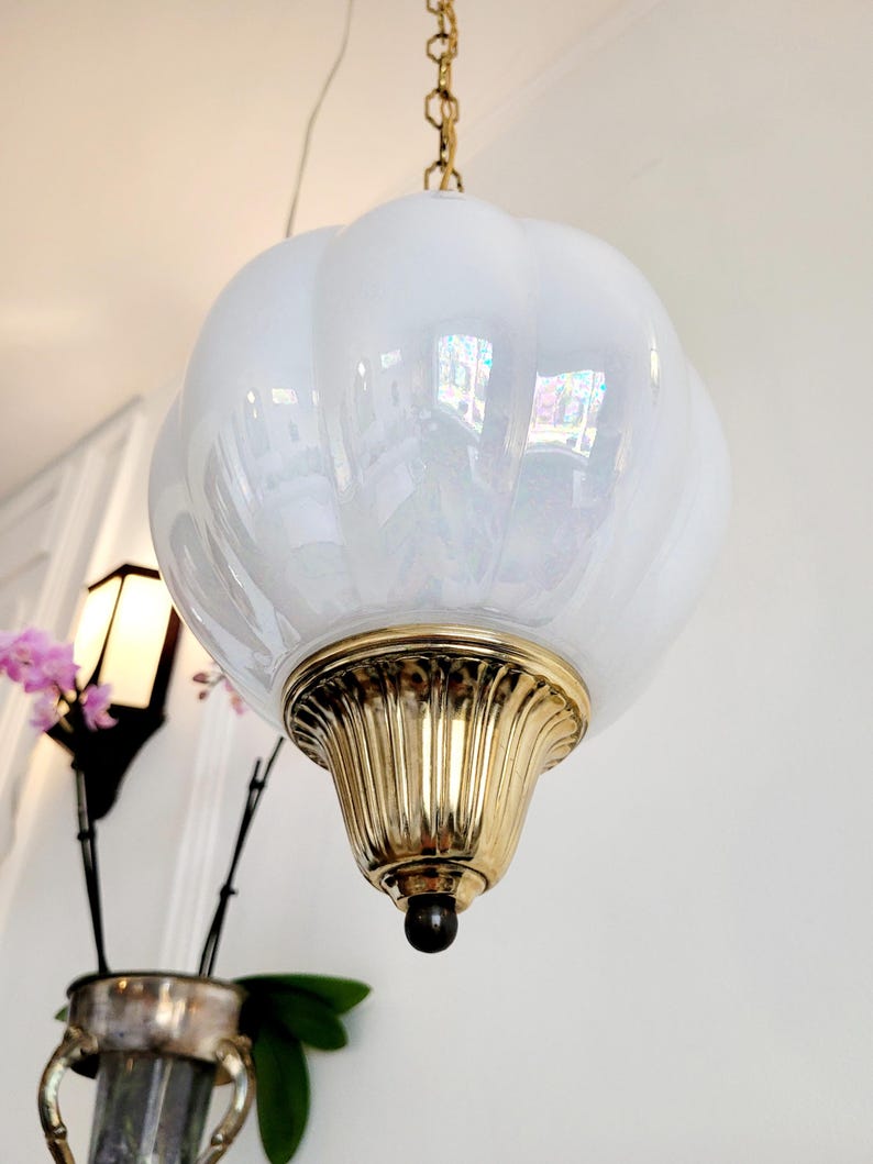 May include: A white iridescent glass pendant light fixture with a brass base and chain.