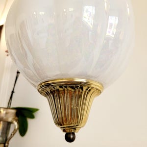 May include: A white iridescent glass globe pendant light fixture with a gold metal base and a small black finial.