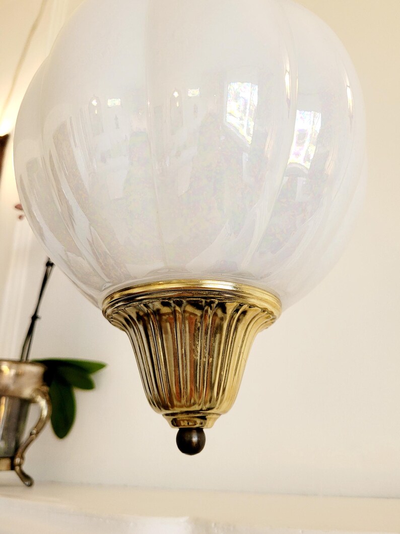 May include: A white iridescent glass globe pendant light fixture with a gold metal base and a small black finial.